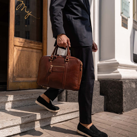 Man in a suit holding a brown Von Baer luxury leather laptop bag