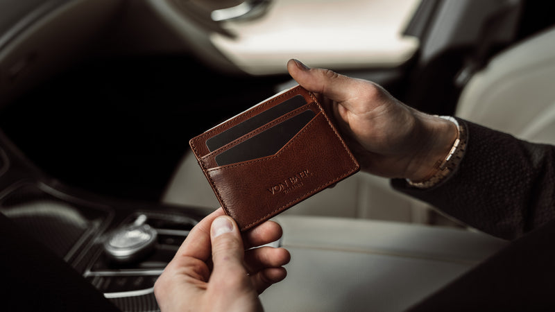 A brown Von Baer minimalist slim leather card holder for men is shown inside a luxurious car.