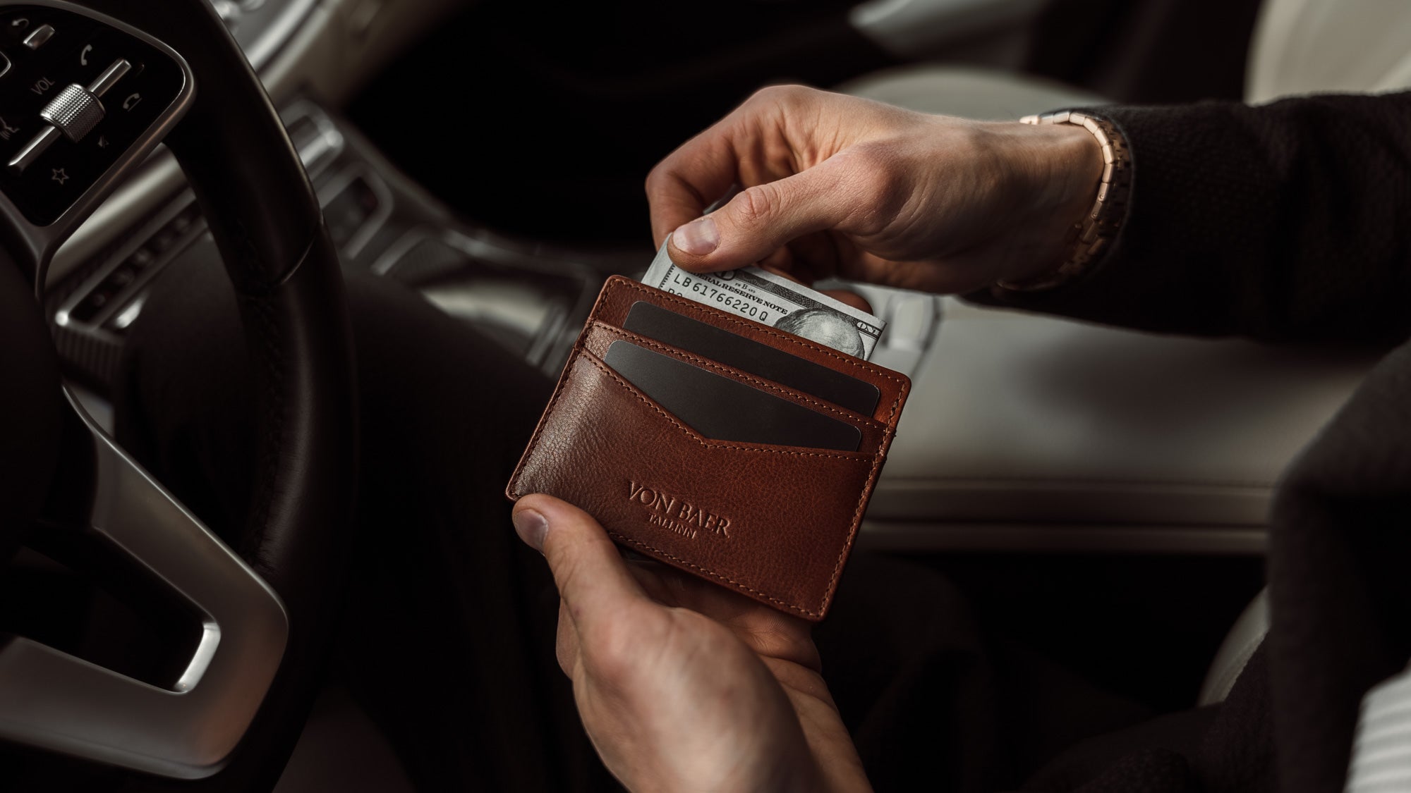 Von Baer minimalist best quality men's slim leather card holder in brown, with cash in hand, slider view.