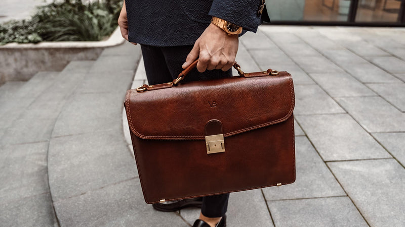 A male model is shown with a solid brown Von Baer No.1 large leather briefcase.
