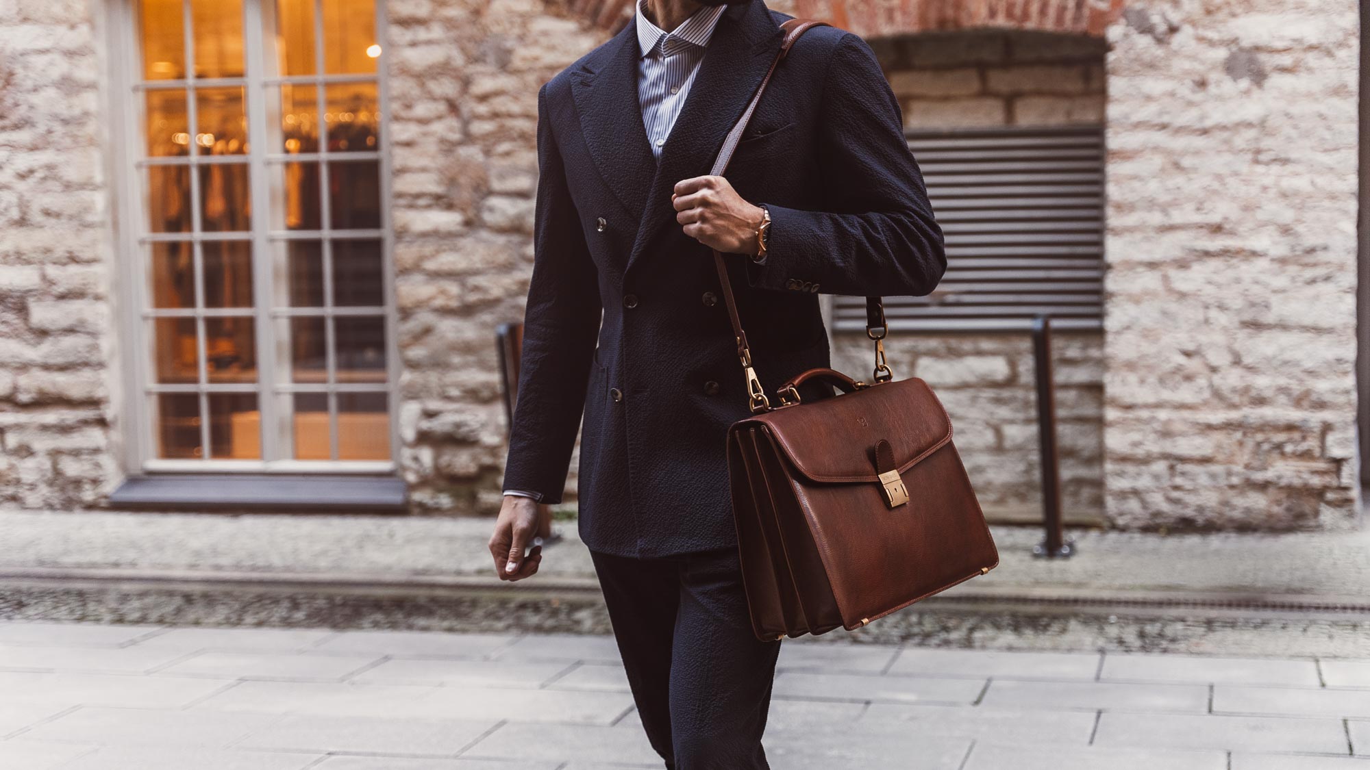 A lawyer is shown carrying a solid brown Von Baer No.1 large leather briefcase for men on the shoulder.