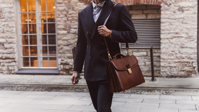 A lawyer is shown carrying a solid brown Von Baer No.1 large leather briefcase for men on the shoulder.