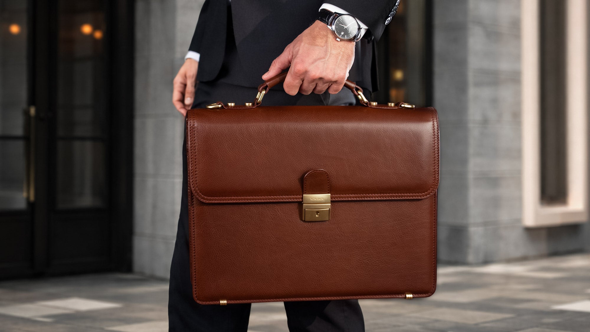 Von Baer No.3 brown full-grain leather men's classic briefcase, held by a man in a suit in a city setting, showcasing luxury and professional style