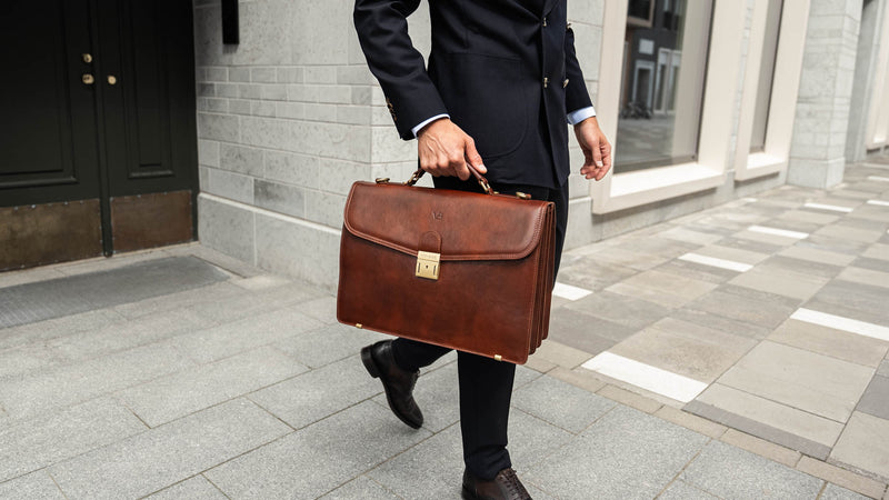 A large, brown Von Baer No.1 luxury high-quality men's leather briefcase for work and documents, held by a man in a suit