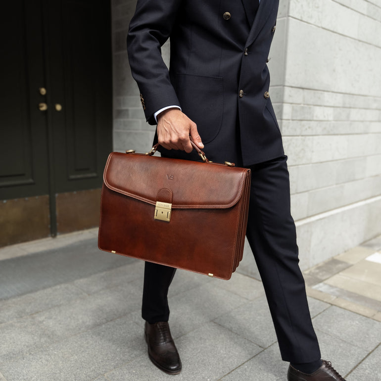 A large, brown Von Baer No.1 luxury men's leather briefcase for work and documents, held by a businessman in a suit