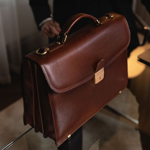 Large brown luxury men’s leather briefcase for work and documents on a table.
