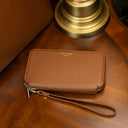 Von Baer origin leather purse on a vintage table near an old lamp and a luxury tote bag