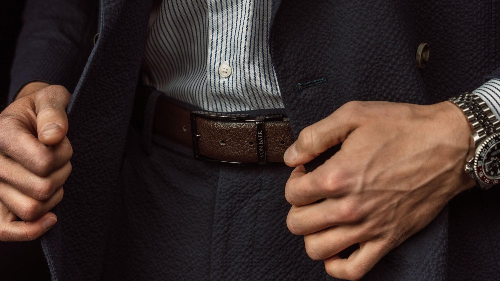 Von Baer Premier luxury reversible natural leather belt for men, showcasing the black and brown sides with a black buckle, worn by a male model.