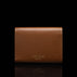 Von Baer Reverie compact cognac pebbled leather wallet for women, shown from the back with debossed Von Baer Tallinn branding, centered against a black background with a subtle reflection below