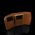 Von Baer Reverie luxury compact cognac pebbled leather wallet for women, shown open with multiple card slots, a gold-tone zipper, and a small gold logo on the interior, displayed on a reflective black surface