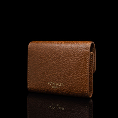 Von Baer Reverie small luxury cognac pebbled leather wallet for women, shown closed in a three-quarter view highlighting its elegant front flap and compact design against a reflective black background