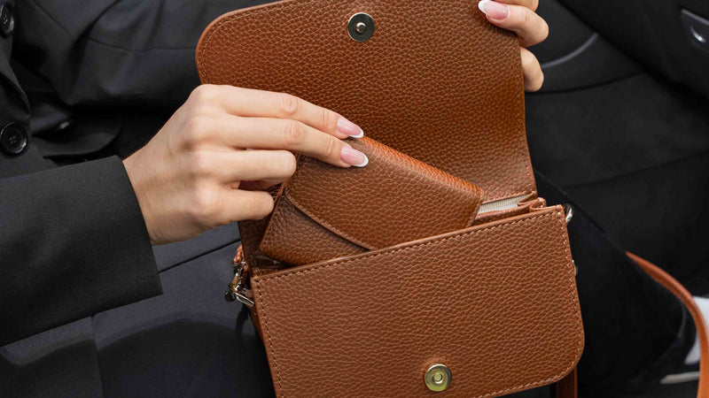 Von Baer Reverie cognac tan women's leather wallet shown tucked into the side pocket of an open Isabella small crossbody bag, captured in a close-up view to display everyday essentials.