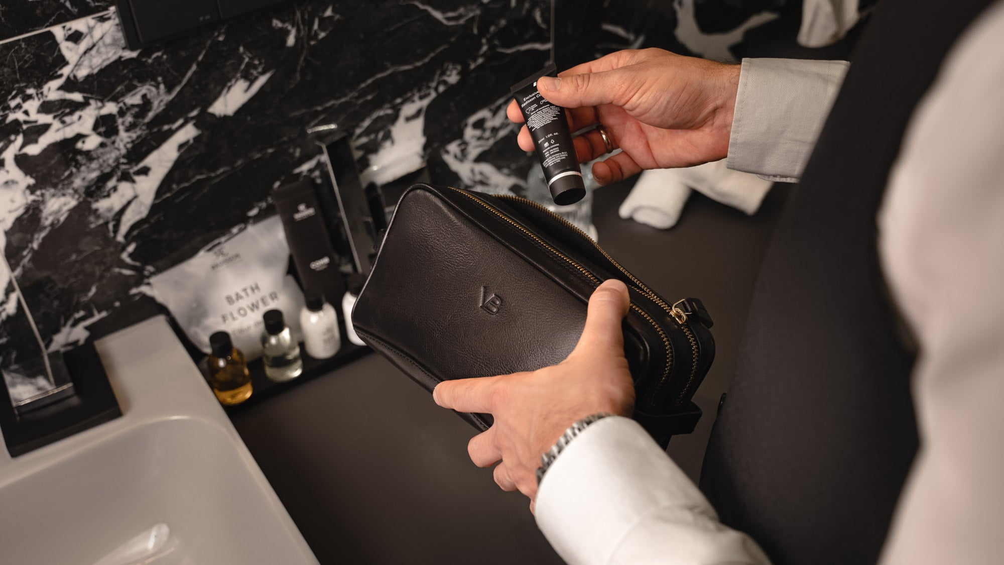 Von Baer superior high-quality luxury full-grain leather wash bag in black, held by a male in the bathroom – slider.