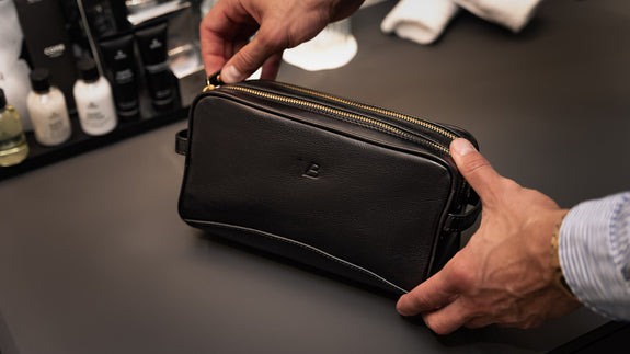 Von Baer superior high-quality luxury full-grain leather wash bag in black, held in the hands – slider.