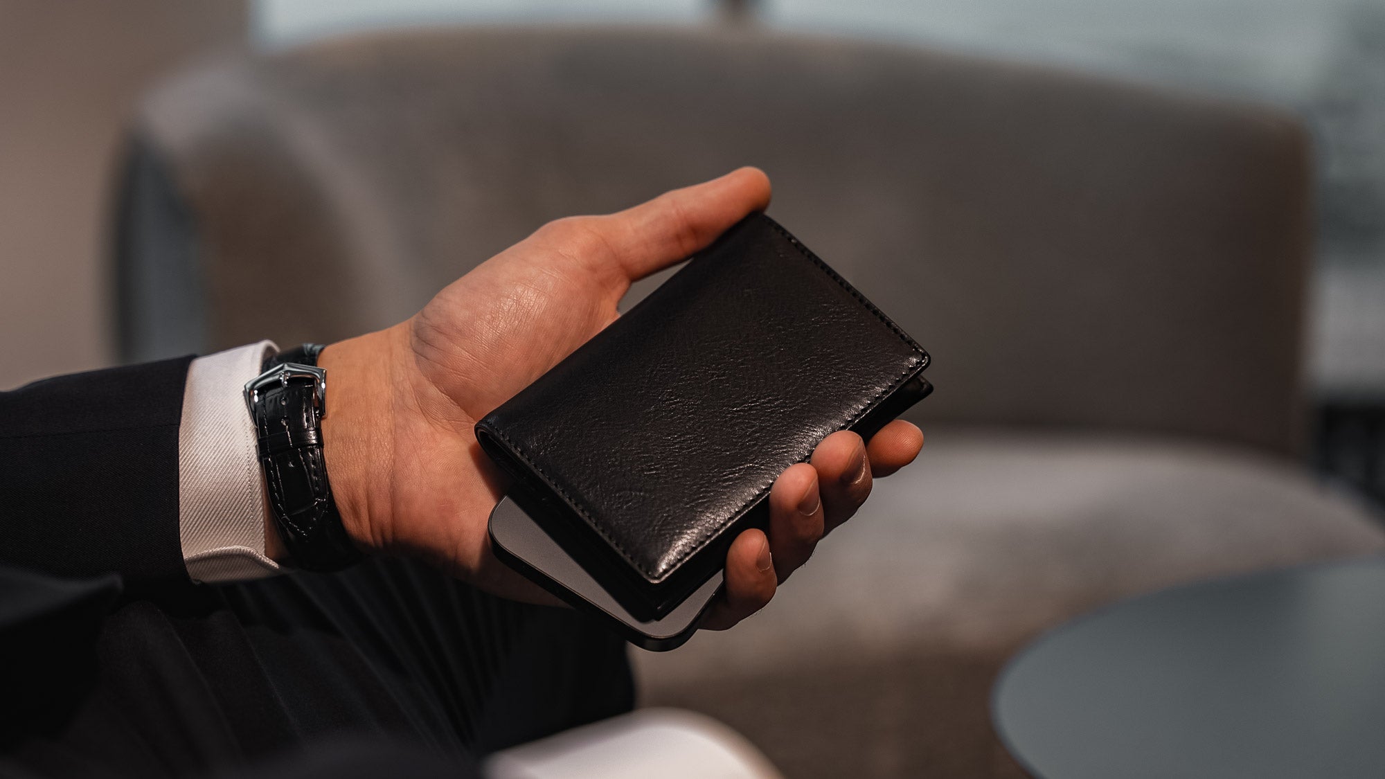 Von Baer Tallinn element leather card case in black color, held by a male model in a luxury hotel, slider.