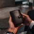 Von Baer Tallinn heritage large men's high-quality leather trifold wallet in black, held by a male model in luxury apartments.