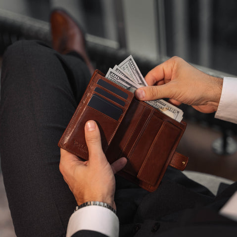 Von Baer Tallinn Heritage large men's high-quality leather trifold wallet in the hands of a male model in luxury apartments, with dollars inside.