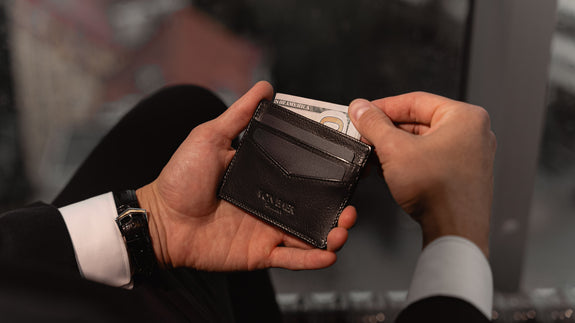 Von Baer Tallinn minimalist high-quality luxury leather card holder in black, held by a well-dressed man in a black suit, slider