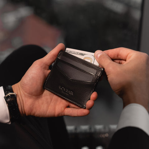 Von Baer Tallinn minimalist high-quality luxury leather card holder, black color, in the hands of a good-looking man in a black suit.