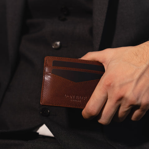 Von Baer Tallinn minimalist high-quality luxury leather card holder in brown held by a stylish man in a black suit