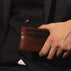 Von Baer Tallinn minimalist high-quality luxury leather card holder in brown held by a stylish man in a black suit