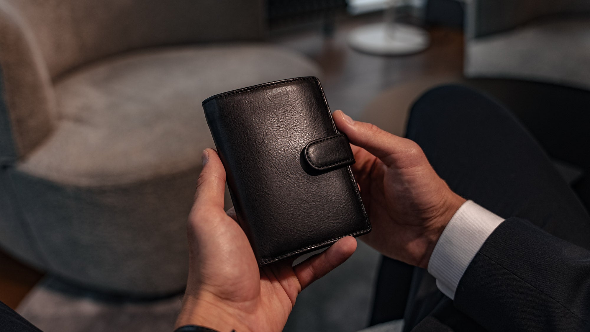 Von Baer Tallinn Washington large men's high-quality leather trifold wallet in black, held by a male model in luxury apartments, showcasing style and sophistication.