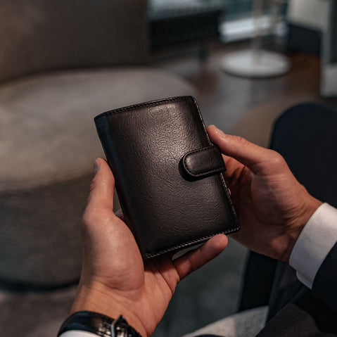 Von Baer Tallinn Washington large men's high-quality leather trifold wallet in black, held by a male model in luxury apartments.