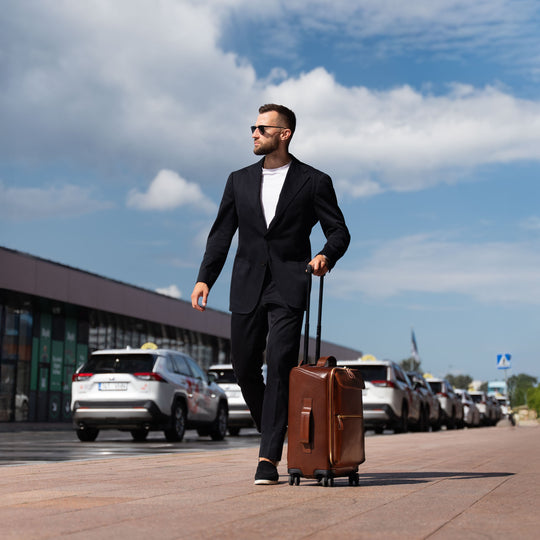 Von Baer Voyager luxury carry-on trolley bag in airport with businessman in black suit