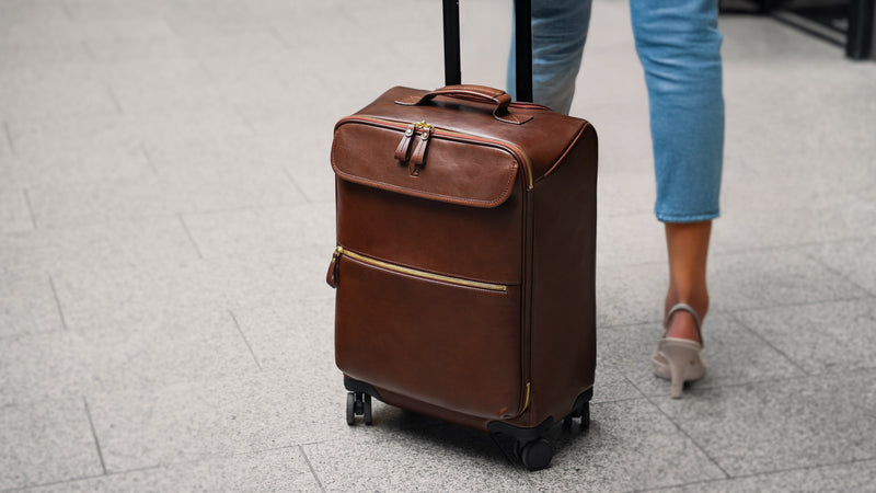 Von Baer Voyager women's luxury leather carry-on trolley bag in airport with female model slider view