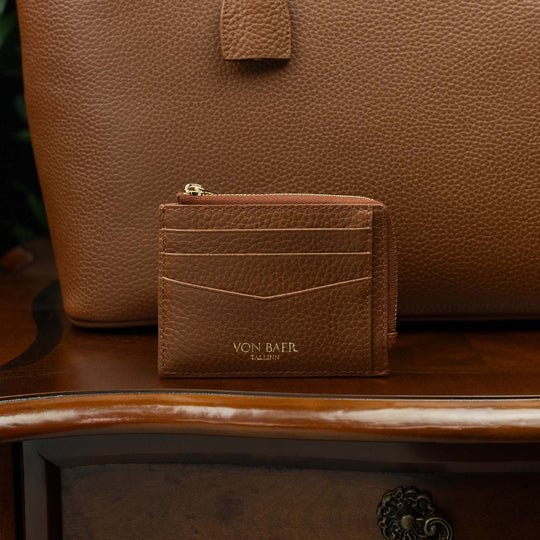 Zipped full grain leather card case with RFID protection on a vintage table with a tote bag in the background
